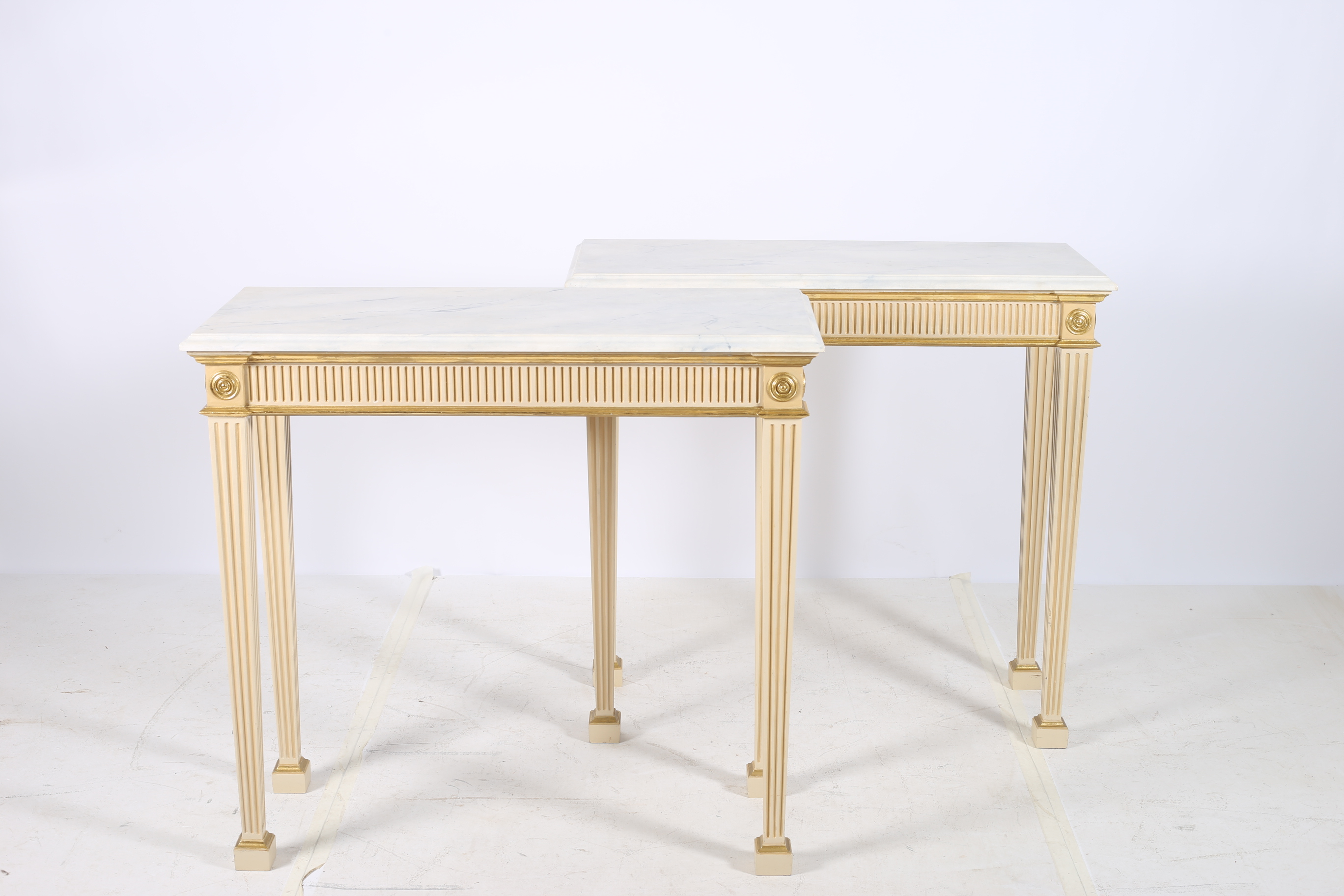 A PAIR OF CONTINENTAL POLYCHROME AND PARCEL GILT CONSOLE TABLES each surmounted with simulated