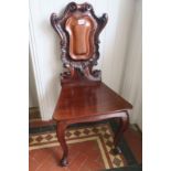 A VERY FINE PAIR OF 19TH CENTURY MAHOGANY HALL CHAIRS each with a carved armorial shape back with