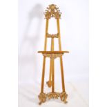 A CONTINENTAL CARVED GILTWOOD ADJUSTABLE EASEL on scroll legs 170cm x 53cm