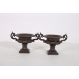 A PAIR OF VICTORIAN DESIGN CAST IRON GARDEN URNS each with semi lobed campana form with scroll