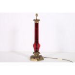 A GOOD 19TH CENTURY BRASS AND RUBY GLASS TABLE LAMP the faceted column above a stylized foliate and
