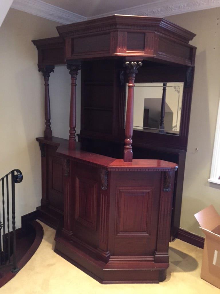 A MAHOGANY BAR UNIT with back panel and mirror and cornice the shaped moulded counter top with