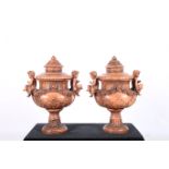 A PAIR OF GLAZED TERRACOTTA LIDDED URNS each moulded in high relief with flower heads and foliage