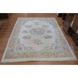 A WOOL RUG the beige ground with central floral panel within a conforming border 260cm x 173cm