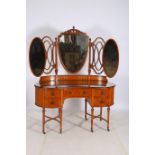 A KIDNEY SHAPED DRESSING TABLE with curved plate glass back and frieze drawers and cupboards 129cm