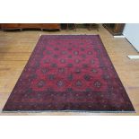 AN AFGHAN KHAN WOOL RUG the wine ground with central panel filled with palmettes hooks and flower