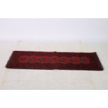 AN AFGHAN AQCHA WOOL RUNNER the wine ground decorated with stylized foliage hooks and palmettes