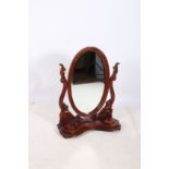 A VICTORIAN DESIGN CARVED MAHOGANY CRUTCH FRAMED MIRROR the oval bevelled glass plate within a