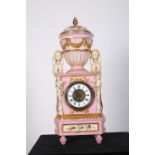 A CONTINENTAL PORCELAIN MANTLE CLOCK surmounted by a lidded urn flanked by two puttees shown seated