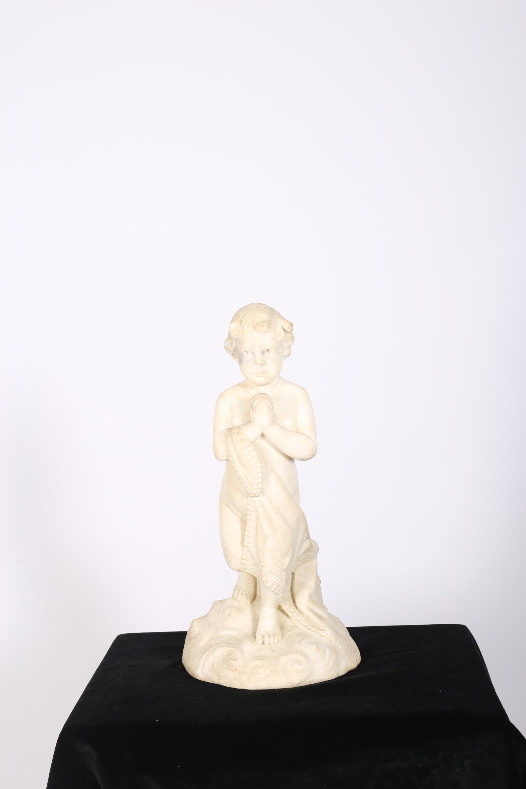 A WHITE MARBLE FIGURE modelled as a young child holding a shawl shown standing on a naturalistic