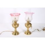 A GOOD PAIR OF 19TH CENTURY BRASS OIL LAMPS converted each with a frosted and ruby glass shade