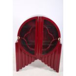 AN ART DECO HARDWOOD AND POLYCHROME DISPLAY CABINET of circular outline with glazed doors and