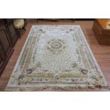 A BEIGE GROUND PATTERNED RUG the central panel filled with flower heads and foliage within a