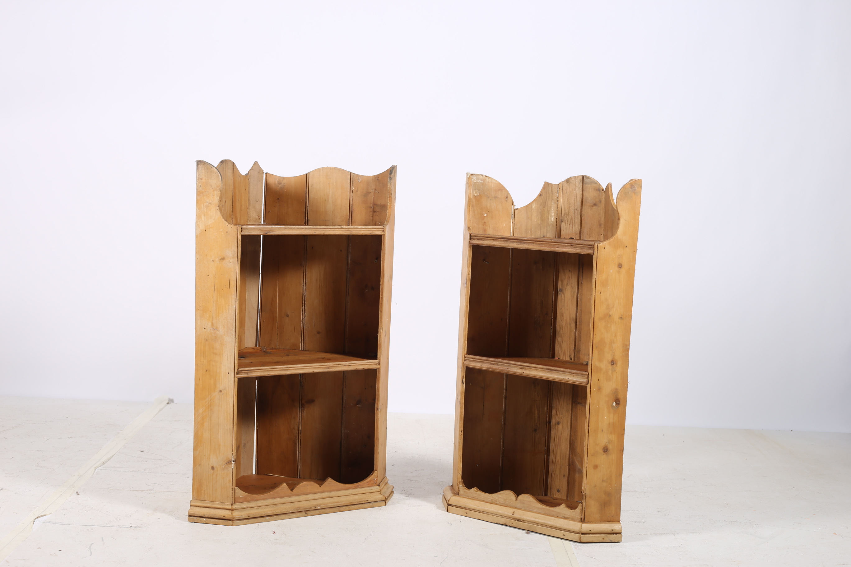 A PAIR OF PINE WALL MOUNTED CORNER SHELVES each with a moulded frieze above two open shelves