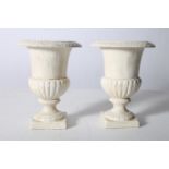 A PAIR OF CAST IRON GARDEN URNS each of semi lobed campana form with circular spreading foot on