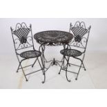A THREE PIECE WROUGHT IRON PATIO SUITE comprising pair of folding chairs each with a scroll top