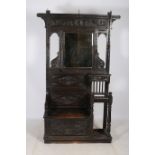 A JACOBEAN DESIGN CARVED OAK HALL STAND with bevelled mirror and hooks above one short drawer with