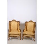 A PAIR OF CONTINENTAL GILTWOOD WINGED CHAIRS each with a foliate and flower head carved top rail