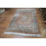 A CHINESE WOOL RUG the light pink and beige ground with central floral panel within a conforming
