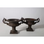 A PAIR OF CAST IRON GARDEN URNS each of semi-lobed campana form with pierced scroll handles above a