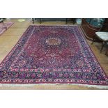 A MASHAD WOOL RUG the wine and indigo ground with central panel filled with stylized flower heads