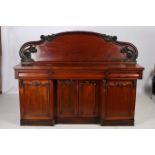 A VICTORIAN MAHOGANY SIDEBOARD of rectangular outline the shaped top with carved and moulded back