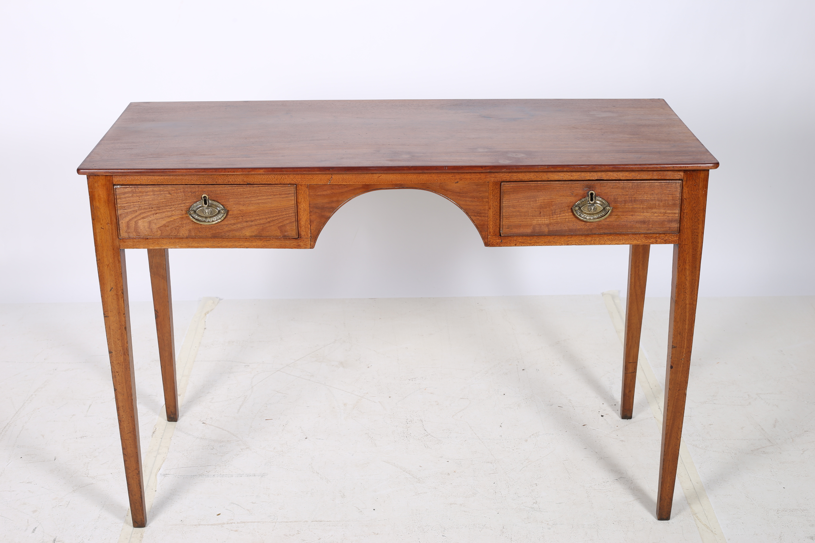 A GEORGIAN MAHOGANY DESK of rectangular outline the shaped top above two short drawers with brass