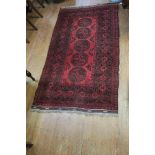 AN ORIENTAL WOOL RUG the red ground with central panel filled with octagonal panels with palmettes