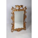 A CONTINENTAL GILTWOOD FLAT FRAMED MIRROR the shaped plate within a pierced flower head and foliate