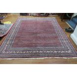 AN ORIENTAL WOOL RUG the wine ground with central panel filled with stylized flowerheads and