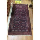 AN ORIENTAL WOOL RUG the wine and black ground with central serrated panels within a conforming