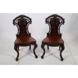 A FINE PAIR OF 19TH CENTURY CARVED MAHOGANY HALL CHAIRS each with a shield shaped back and carved