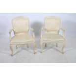 A PAIR OF CONTINENTAL CREAM PAINTED ELBOW CHAIRS each with a foliate carved top rail with