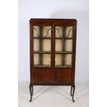 A CIRCA 1950s MAHOGANY CHINA DISPLAY CABINET the shaped top above astragal glazed doors on cabriole