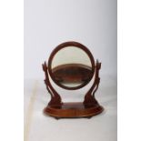 A 19TH CENTURY MAHOGANY CRUTCH FRAME MIRROR the oval plate raised on carved supports and shaped