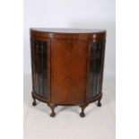 A RETRO MAHOGANY SIDE CABINET of demilune outline the shaped top above a blind panelled door
