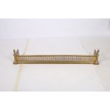 A 19TH CENTURY BRASS FENDER with pierced frieze and bead work decoration between reeded columns and