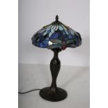 A TIFFANY DESIGN BRONZED TABLE LAMP the multicoloured mushroom shape shade above a baluster column