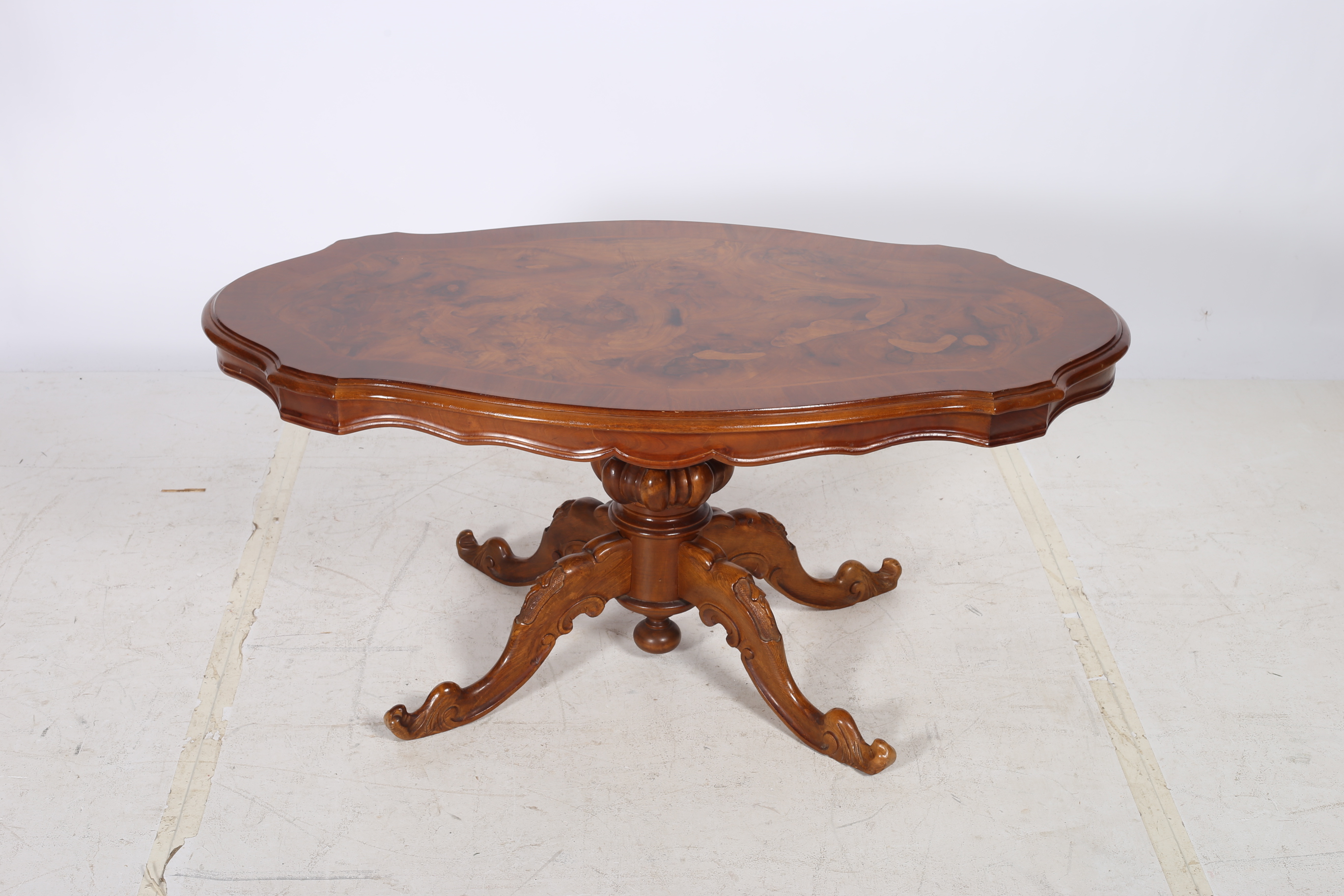 A CONTINENTAL WALNUT CROSS BANDED COFFEE TABLE of serpentine outline the shaped top above a