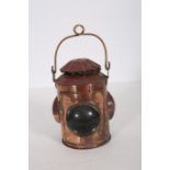 A COPPER RAILWAY LAMP of cylindrical form with three bulbous glazed panels and carrying handle 38cm