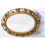 A CONTINENTAL CARVED WOOD MIRROR the oval plate within a C scroll pierced and shell frame 107cm x