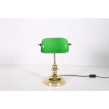 A BRASS OPALINE AND GREEN GLASS DESK LAMP with adjustable shade above a turned column on spreading