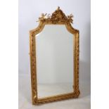 A CONTINENTAL GILT FRAMED MIRROR the shaped bevelled glass plate within a flower head and foliate