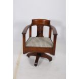 AN OAK TUB SHAPED SWIVEL LIBRARY CHAIR with carved vertical splat and upholstered seat on revolving