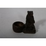 A BLACK FOREST CARVED WOOD FIGURE modelled as a bear shown seated beside a well with brass liner
