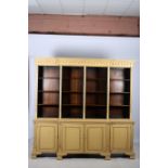 A MAHOGANY AND POLYCHROME BOOKCASE of breakfront outline the dentil moulded cornice above sixteen