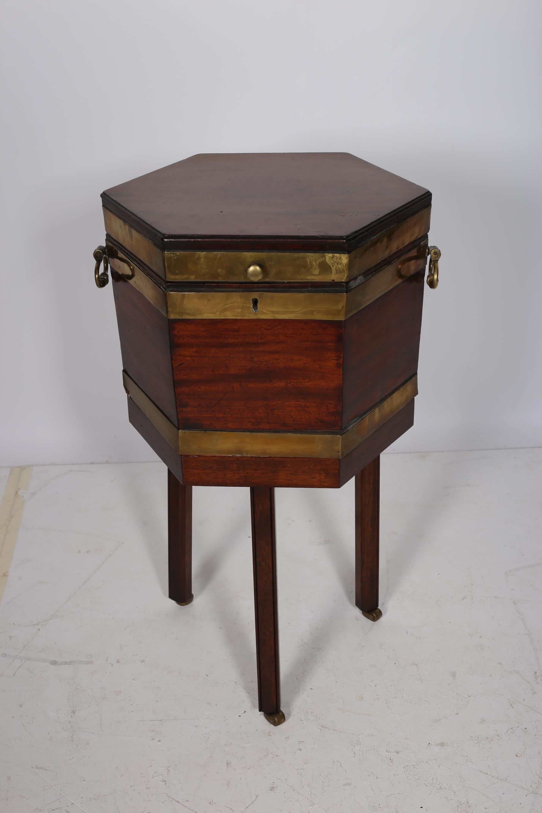 A GEORGIAN MAHOGANY AND BRASS BOUND CELLARETTE of octagonal outline the hinged lid with brass drop