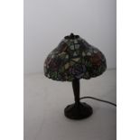 A TIFFANY DESIGN BRONZED TABLE LAMP the multicoloured mushroom shaped shade above a reeded column