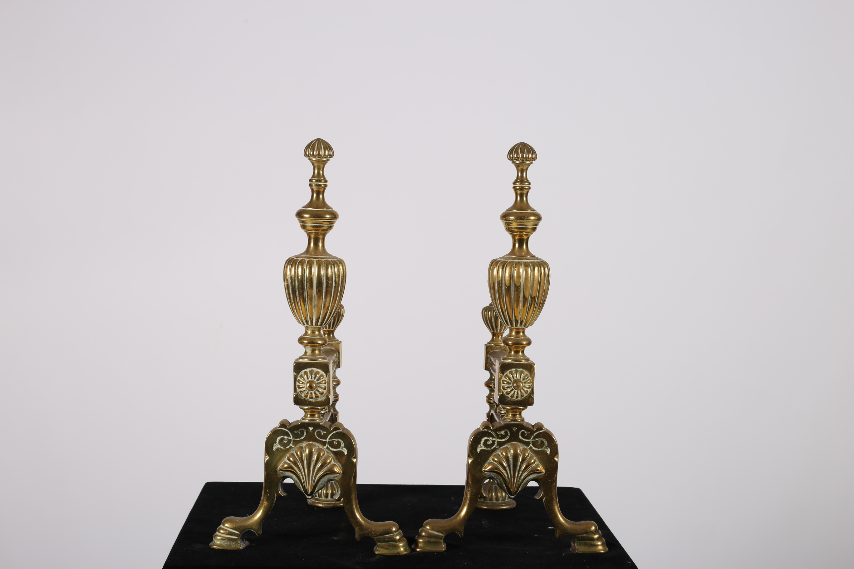 A GOOD PAIR OF 19TH CENTURY BRASS FIRE DOGS each with an urn finial raised on a platform base