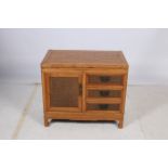 A HARDWOOD SIDE CABINET of rectangular outline with frieze drawers and cupboard with rattan panels